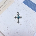 Detailed macro view of a silver alloy cross pendant featuring a radiant blue opal center - Fleur-de-lis Oval Cross / Blue + White K Pattern