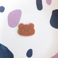 Detail eines niedlichen Cartoon-Bären-Acryl-Zubehörs mit Goldstempel-Gesichtsmotiven - Braun Waschbär