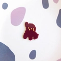 Close-up of cute burgundy poodle acrylic accessory with glossy finish and golden details - Dark Red Dog