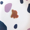 Macro shot of cute cartoon dog acrylic pendant with golden facial details for DIY hair clips - Coffee Dog