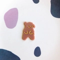 Macro shot of a brown-pink resin bear DIY hair accessory with gold glitter facial details - Coffee Standing Dog