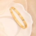 Elegante gouden armband met hartgravure en kristallen op een wit keramisch dienblad - Goud