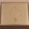 Détail de la chevillère en acier titane avec pendentif gourde dorée et breloque Fu - Or