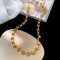 Vergoldete Knotenkette im minimalistischen Industriestil auf weißem Seidenstoff - Gold