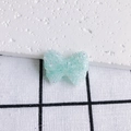 Dettaglio macro di ciondolo a fiocco in acrilico glitter menta per gioielli DIY - Verde menta