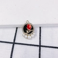 Nahaufnahme von Rosenanhänger mit roter Blüte, Glitzerrahmen und fünf weißen Perlen - Goldrahmen Schwarze Basis Rosenstil