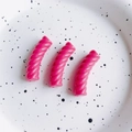 Primo piano di tre perline a spirale in resina magenta per gioielli fai-da-te su un piatto - Rosa Vivo Piccolo (23#)