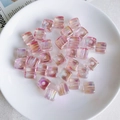 Macro shot of 12mm pink acrylic sugar cube beads with iridescent finish for DIY crafts - Light Pink to Transparent Gradient