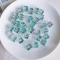 Makro-Detail von 12mm Aurora-Acrylwürfelperlen mit Mittelloch für DIY-Handyketten - Irisierendes Blaugrün