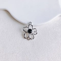 Gros plan détaillé d'un pendentif fleur argenté avec gemme noire pour bijoux - Fleur Creuse Argentée Strass Noir (5#)