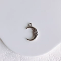 Detail shot of silver moon pendant with man-in-the-moon relief on white tray - Crescent Moon Pendant (White K)