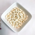 Oval cream-colored spray painted alloy beads in a white bowl for DIY jewelry making - Cream