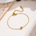 Detailaufnahme einer goldfarbenen Titanhalskette mit Zirkonia-Anhänger auf beigem Naturstein - 7718 Einzel-Zirkon Armband / Gold