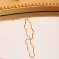 Minimalistischer goldener Ring mit Wellentextur und feinem Schimmer auf einer Reflexionsfläche - US 5 / Gold