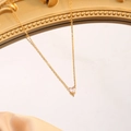 Nahaufnahme eines herzförmigen rosa Edelstein-Anhängers an einer goldenen Kette - April (Weiß)