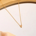 Macro detail of heart-shaped orange gemstone necklace on gold chain with silk backdrop - December (Champagne Gold)