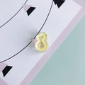 Primo piano di una mini pinza per capelli giallo pallido a forma di otto su carta pastello - Giallo