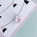 Primo piano di un fermaglio per capelli in acrilico rosa a forma di 8 su carta illustrata - Rosa