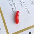 Macro shot of a red translucent acrylic curved tube bead for DIY jewelry making - Red