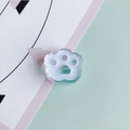 Detailed close-up of a cute acrylic cat paw charm with a white paw pad and green edge - Blue