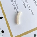 Close-up of a cream-colored curved tube bead with marble texture for DIY jewelry making - Off-White Texture