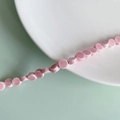 Detailed view of pink round ceramic beads on a white plate with a mint green background - Pink Flat Round Style (2#)