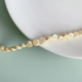 Detail of light yellow flat round ceramic beads with smooth glaze on a white porcelain plate - Cream Flat Round Style (7#)