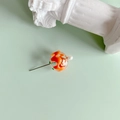 Detail of a handmade glass bead with orange waves, pearl accent, and a metal pin fastener - Orange Wave Green Dotted Style (4#)