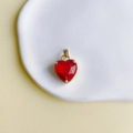 Macro d'un pendentif coeur en pierre rouge avec bordure en cuivre doré sur un plateau - Rouge Vif (4#)