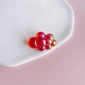 Macro shot of a red acrylic chubby cloud charm with aurora iridescent finish on a tray - Size 6