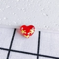 Macro shot of a red heart-shaped DIY bead with yellow starbursts and white polka dots - Red Starburst Polka Dot Style (16#)