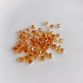 Close-up of amber faceted glass cube beads with central holes for DIY jewelry making - Amber