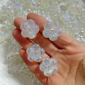 Vista macro di perle a forma di fiore in acrilico iridescente tenute in mano per bijoux - Accessorio Fiore a Cinque Petali 3D Cangiante - Aurora (A67#)