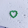 Macro shot of an emerald green hollow heart pendant for DIY jewelry crafts - Hollow Green Heart