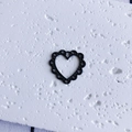 Macro detail of black openwork heart charm with scalloped edges for DIY jewelry making - Hollow Black Heart