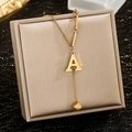 Detail of gold stainless steel Y-shaped necklace with letter A pendant and small cube tassel - Letter A