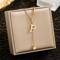 Gold stainless steel necklace with letter P pendant on champagne satin jewelry box - Letter P