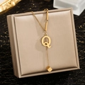 Macro detail of gold letter Q pendant with tassel cube on elegant jewelry box - Letter Q