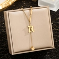 Macro shot of gold letter R pendant necklace with tassel design on jewelry box - Letter R