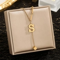 Macro detail of gold Y-shaped necklace featuring an S letter charm and cube pendant - Letter S