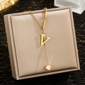 Detailed shot of golden V-letter pendant necklace with asymmetric chain and square charm - Letter V