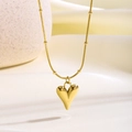 Primer plano de un colgante de corazón dorado en una cadena de serpiente sobre tela - Corazón de Melocotón (8879)