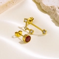Detailaufnahme asymmetrischer goldener Ohrstecker mit rotem Edelstein und weißen Kristallen - Stier (Gold)