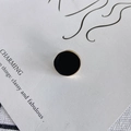 Détail de boucles d'oreilles rondes en émail noir avec bordure dorée sur carte d'affichage - Noir (#2)