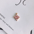 Detailaufnahme eines rautenförmigen Anhängers mit rosa Zirkonia-Steinen und goldener Basis - Rosa
