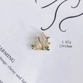 Detail eines goldenen M-Emaille-Anhängers mit grünen Blättern und rosa Schmetterling - M