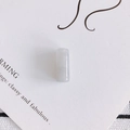 Vista macro di una perla cilindrica in resina bianca traslucida su carta sobria - 6# Grigio
