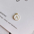 Macro view of a round white enamel letter A pendant with gold-plated alloy frame for DIY jewelry - Style A