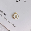 Macro shot of gold circular letter B pendant with white enamel for DIY jewelry making - Style B