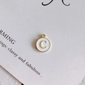 Close-up of golden alloy letter C charm with white enamel finish for DIY jewelry making - Style C